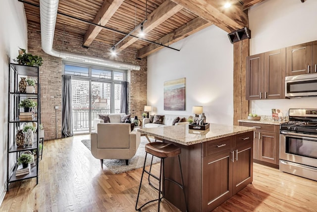 kitchen with brick wall, a towering ceiling, and appliances with stainless steel finishes