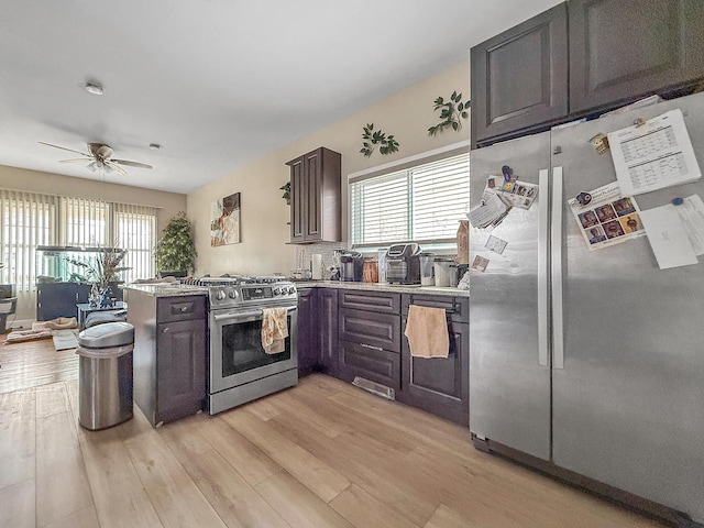 kitchen with light wood-style flooring, a peninsula, appliances with stainless steel finishes, and a healthy amount of sunlight