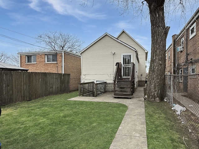 rear view of house featuring cooling unit, a fenced backyard, and a yard
