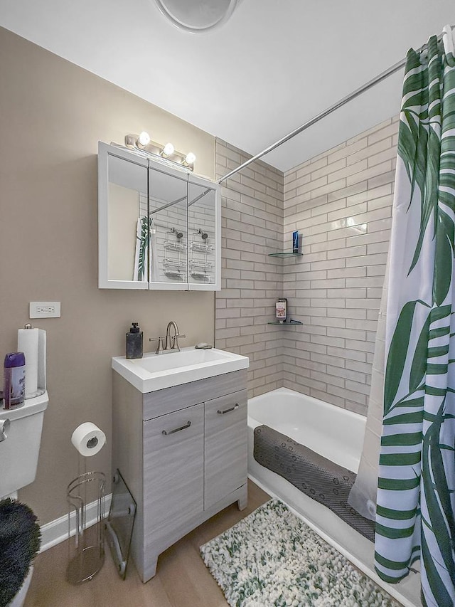 full bath with baseboards, shower / bathtub combination with curtain, toilet, and vanity