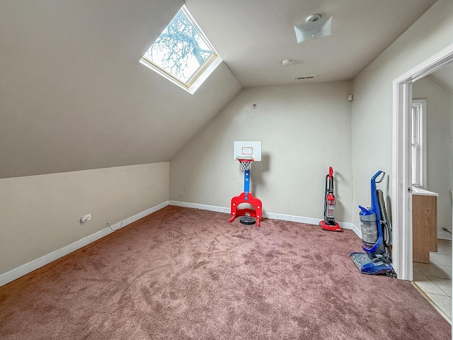 playroom featuring carpet floors, baseboards, vaulted ceiling with skylight, and visible vents