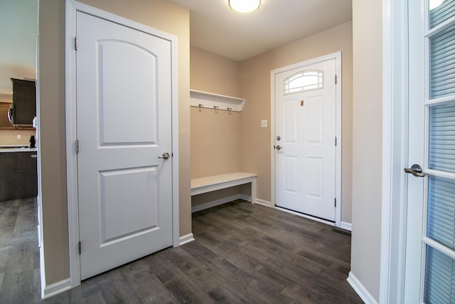 mudroom featuring dark wood-type flooring and baseboards