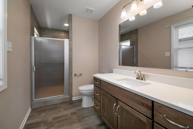 full bathroom featuring vanity, toilet, a shower stall, visible vents, and wood finished floors