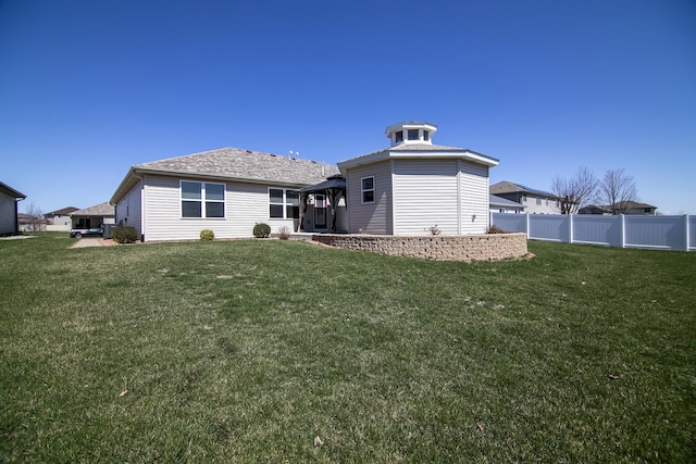 rear view of house with a gazebo, a yard, and fence