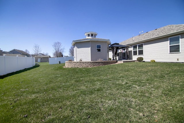 rear view of house with a gazebo, fence, and a lawn