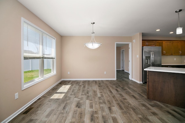 kitchen featuring baseboards, stainless steel refrigerator with ice dispenser, visible vents, dark wood finished floors, and hanging light fixtures