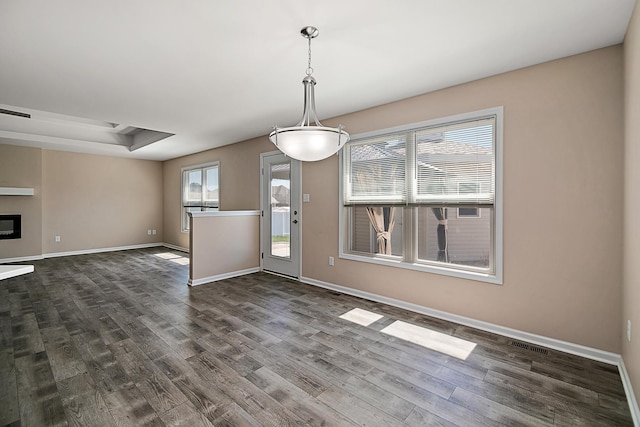 unfurnished dining area with dark wood-style flooring and baseboards
