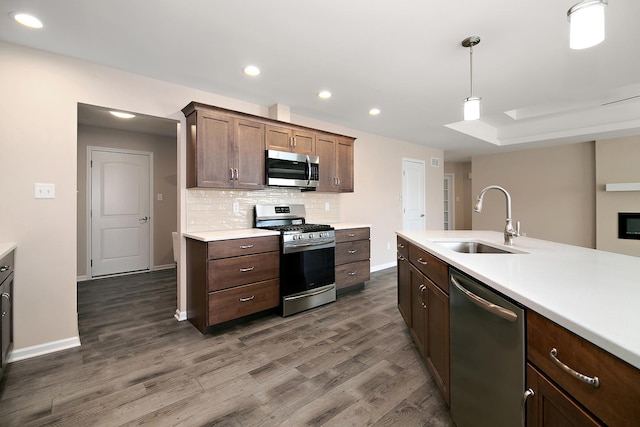 kitchen featuring recessed lighting, appliances with stainless steel finishes, light countertops, a sink, and baseboards
