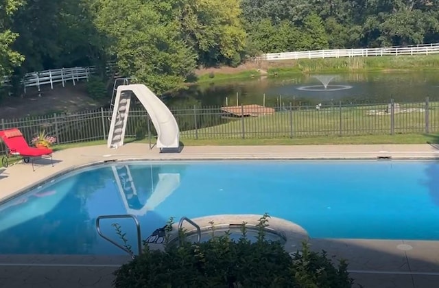 view of swimming pool with a yard, a water view, a water slide, fence, and a fenced in pool