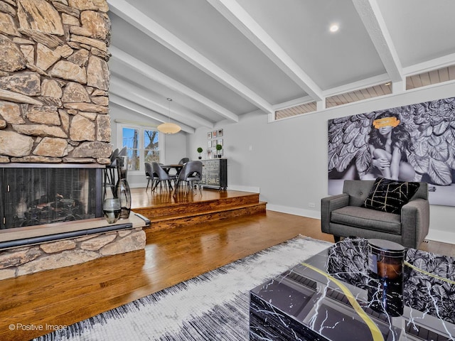 living room featuring baseboards, lofted ceiling with beams, wood finished floors, and a fireplace