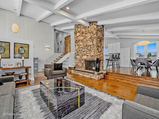 living room with stairs, wood finished floors, beam ceiling, a fireplace, and baseboards