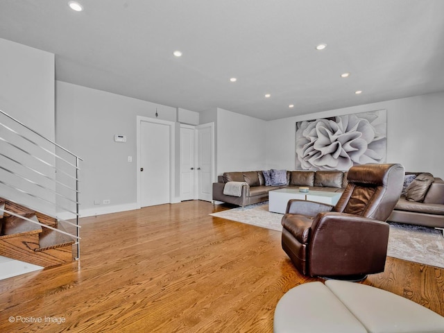 living area with recessed lighting, wood finished floors, and stairway