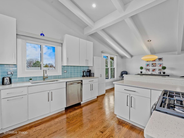 kitchen with stainless steel dishwasher, a sink, light countertops, lofted ceiling with beams, and light wood finished floors