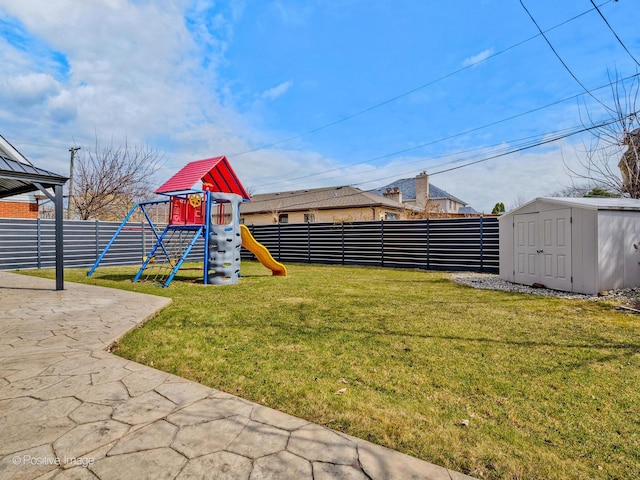 view of yard featuring an outbuilding, a fenced backyard, a playground, and a shed