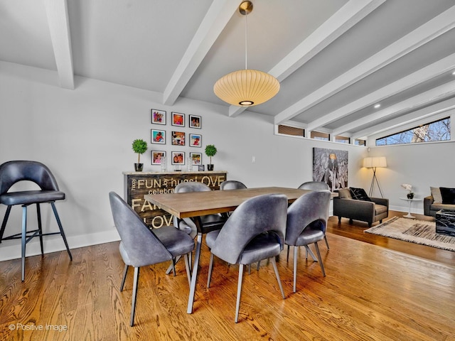 dining room with baseboards, lofted ceiling with beams, and wood finished floors