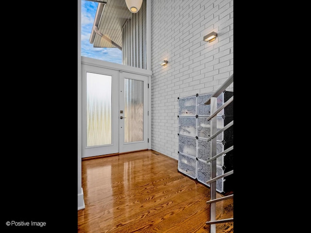 entryway featuring french doors, brick wall, and wood finished floors