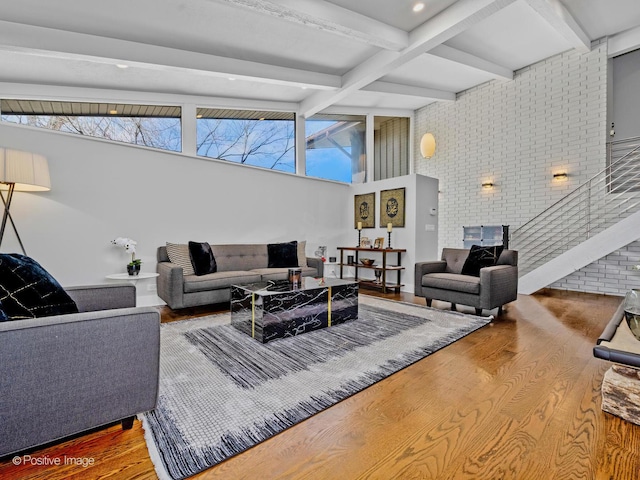 living area featuring stairs, a towering ceiling, wood finished floors, and beamed ceiling
