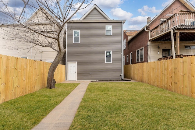 back of house with a fenced backyard and a lawn