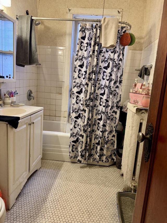 bathroom featuring shower / bath combination with curtain, vanity, and tile walls