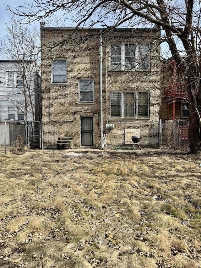 back of property featuring a chimney, fence, and brick siding