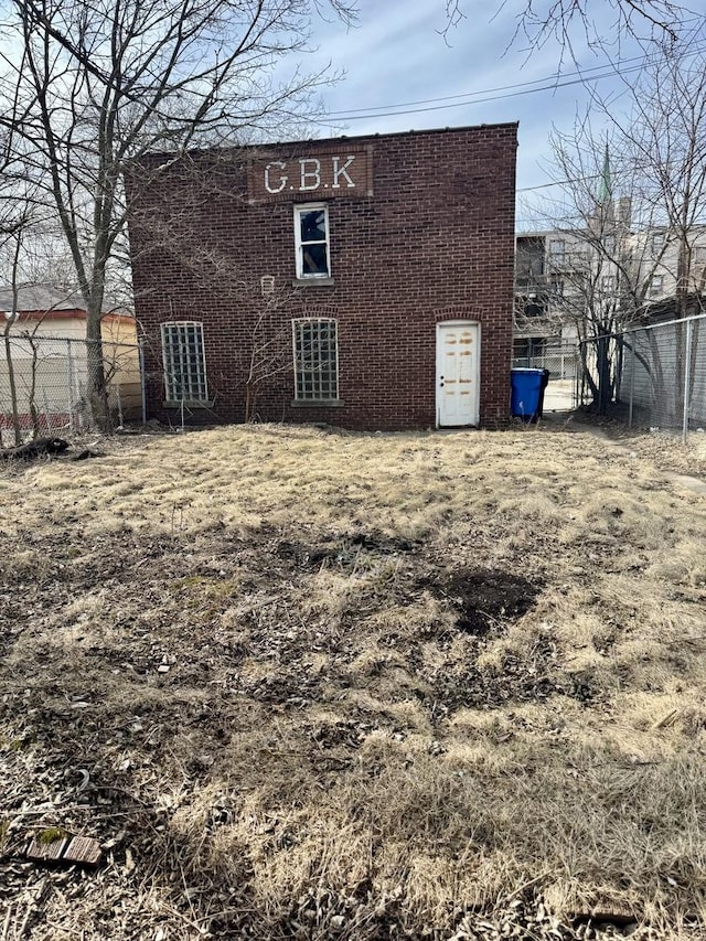 rear view of property featuring brick siding and fence