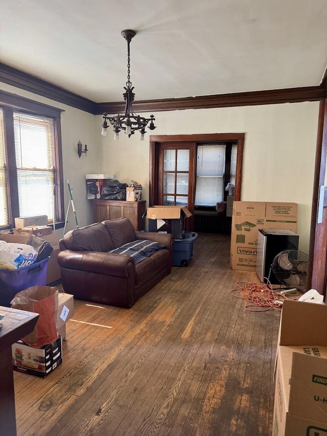 living room with crown molding, a chandelier, and dark wood finished floors