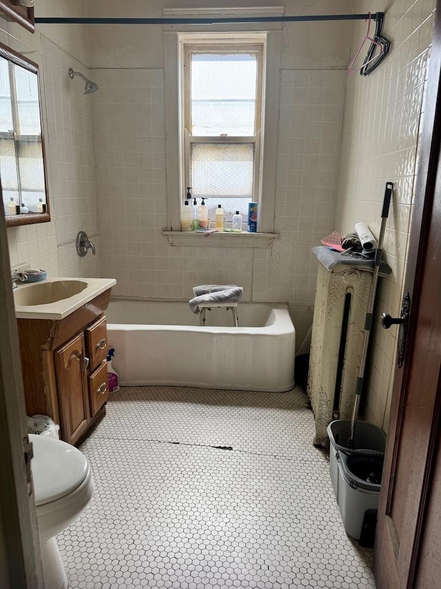 full bathroom featuring toilet, vanity, a healthy amount of sunlight, and tile walls