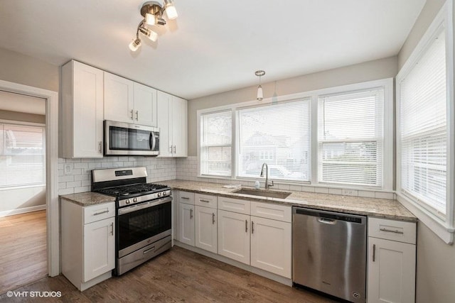 kitchen with stainless steel appliances, tasteful backsplash, white cabinetry, a sink, and dark wood-style floors