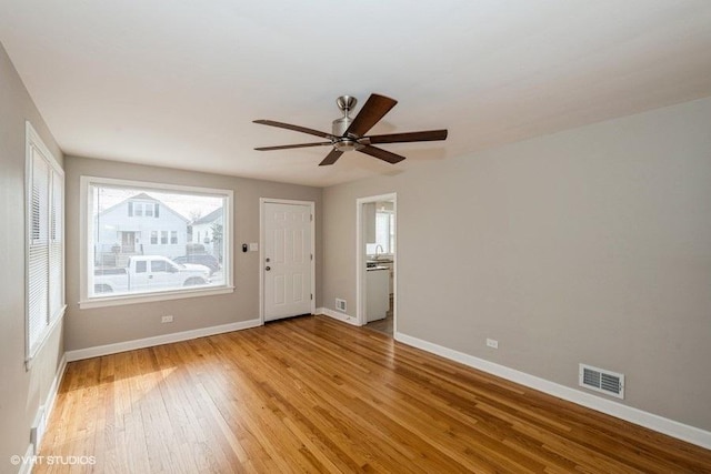 spare room with baseboards, visible vents, light wood-style floors, and a ceiling fan