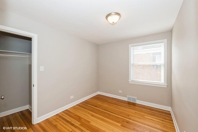unfurnished bedroom featuring baseboards, a closet, light wood finished floors, and visible vents