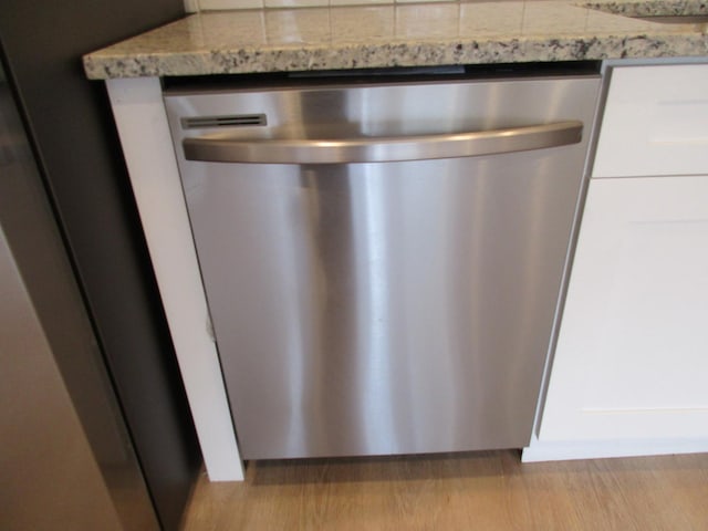 interior details with light stone counters, wood finished floors, and dishwasher