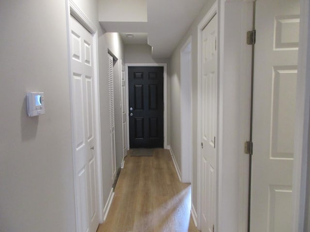 hall with baseboards and light wood-type flooring