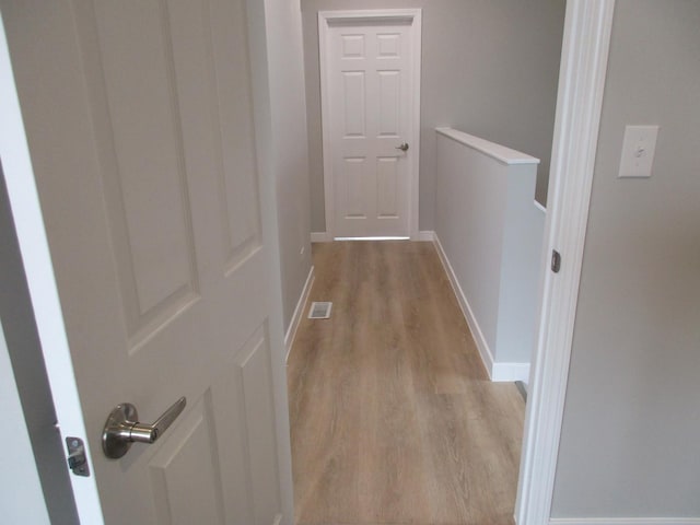 corridor featuring light wood-style flooring, baseboards, and visible vents