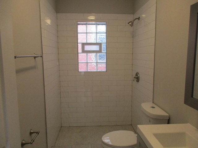 full bath featuring toilet, tiled shower, and vanity