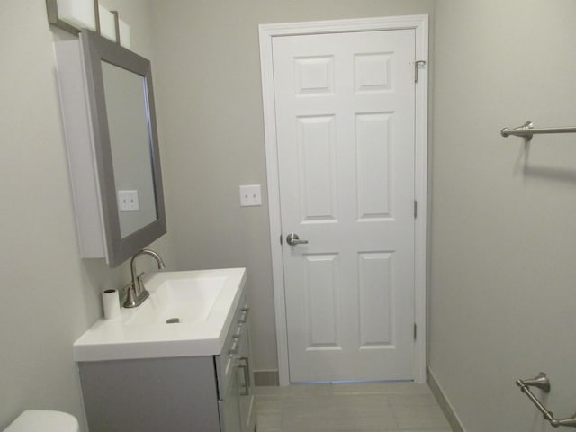 bathroom with baseboards, toilet, and vanity