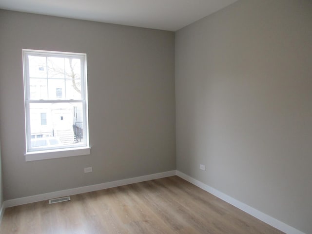 empty room featuring light wood finished floors, baseboards, and visible vents