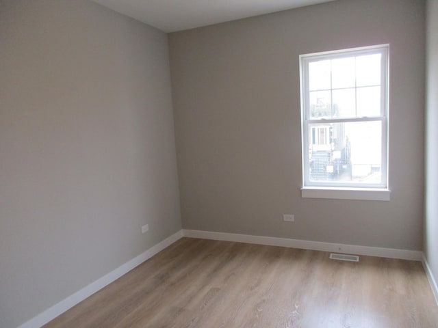 empty room featuring baseboards, visible vents, and light wood-type flooring