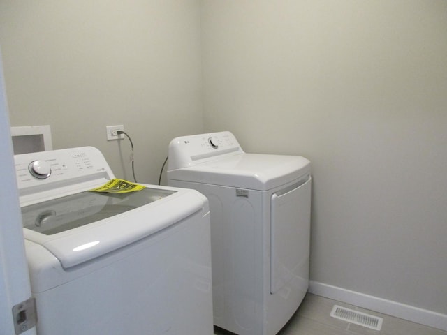 laundry room with washer and clothes dryer, light tile patterned floors, baseboards, visible vents, and laundry area