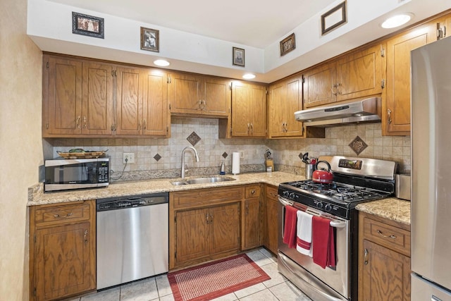 kitchen with light tile patterned floors, under cabinet range hood, decorative backsplash, stainless steel appliances, and a sink