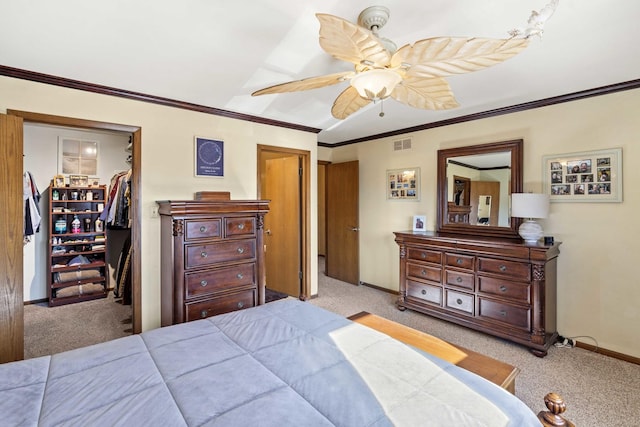 carpeted bedroom featuring visible vents, baseboards, a closet, ornamental molding, and a walk in closet