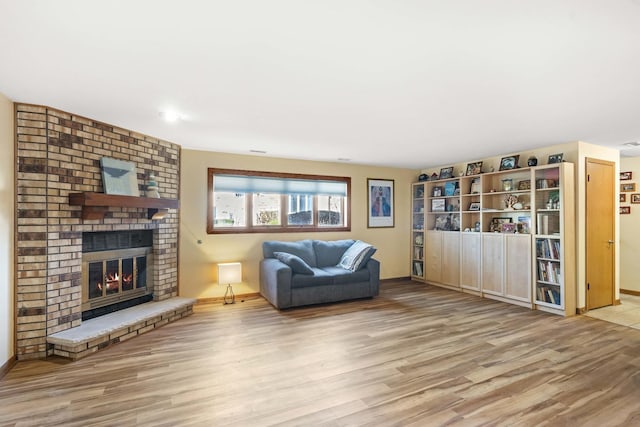 unfurnished living room with baseboards, wood finished floors, and a brick fireplace