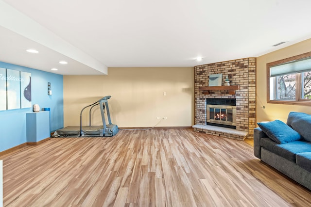 exercise room with visible vents, baseboards, a brick fireplace, recessed lighting, and wood finished floors
