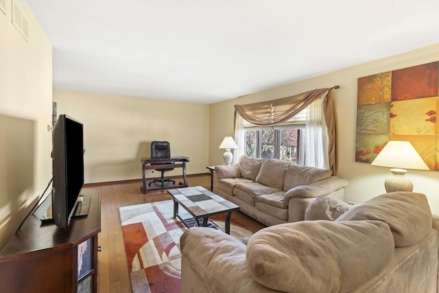 living area with visible vents, baseboards, and wood finished floors