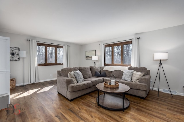 living room featuring baseboards, visible vents, wood finished floors, and a healthy amount of sunlight