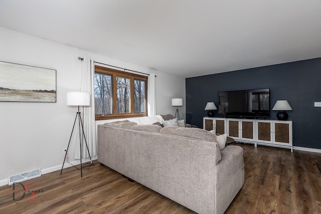 living area with dark wood finished floors, baseboards, and visible vents