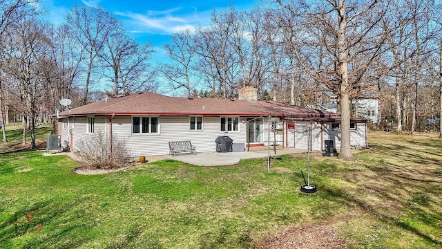 back of property with a lawn, a chimney, cooling unit, and a patio
