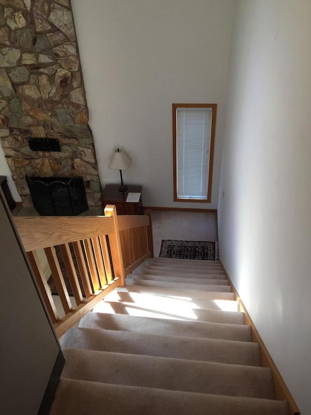 stairs featuring a stone fireplace