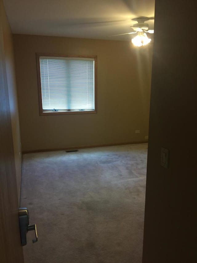 empty room with baseboards, a ceiling fan, visible vents, and carpet floors