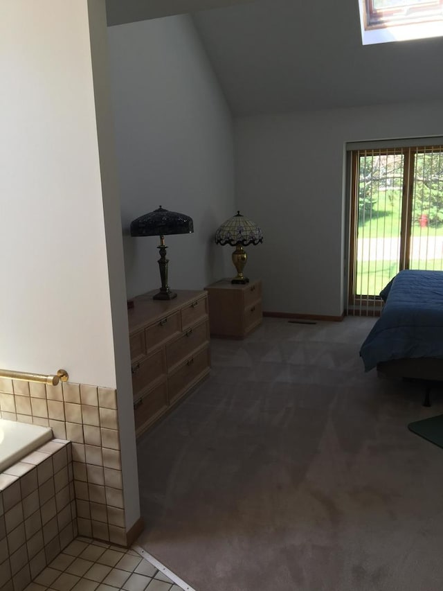 bedroom featuring light colored carpet, baseboards, lofted ceiling with skylight, and access to exterior