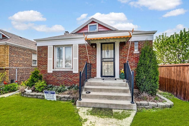 view of front of home with fence, a front yard, and brick siding